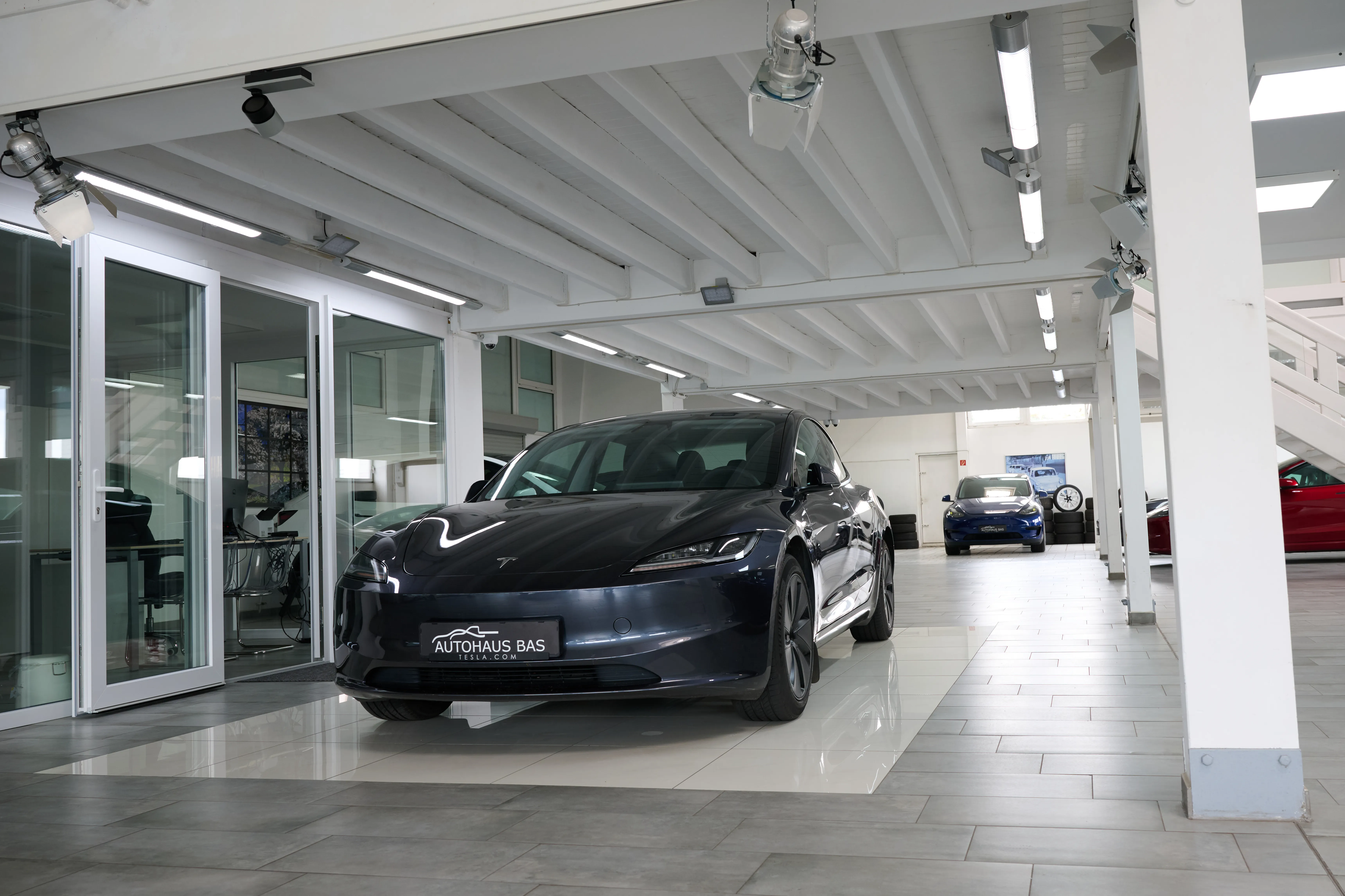 Dunkelblauer Tesla Model 3 von vorn im Showroom des Autohaus Bas