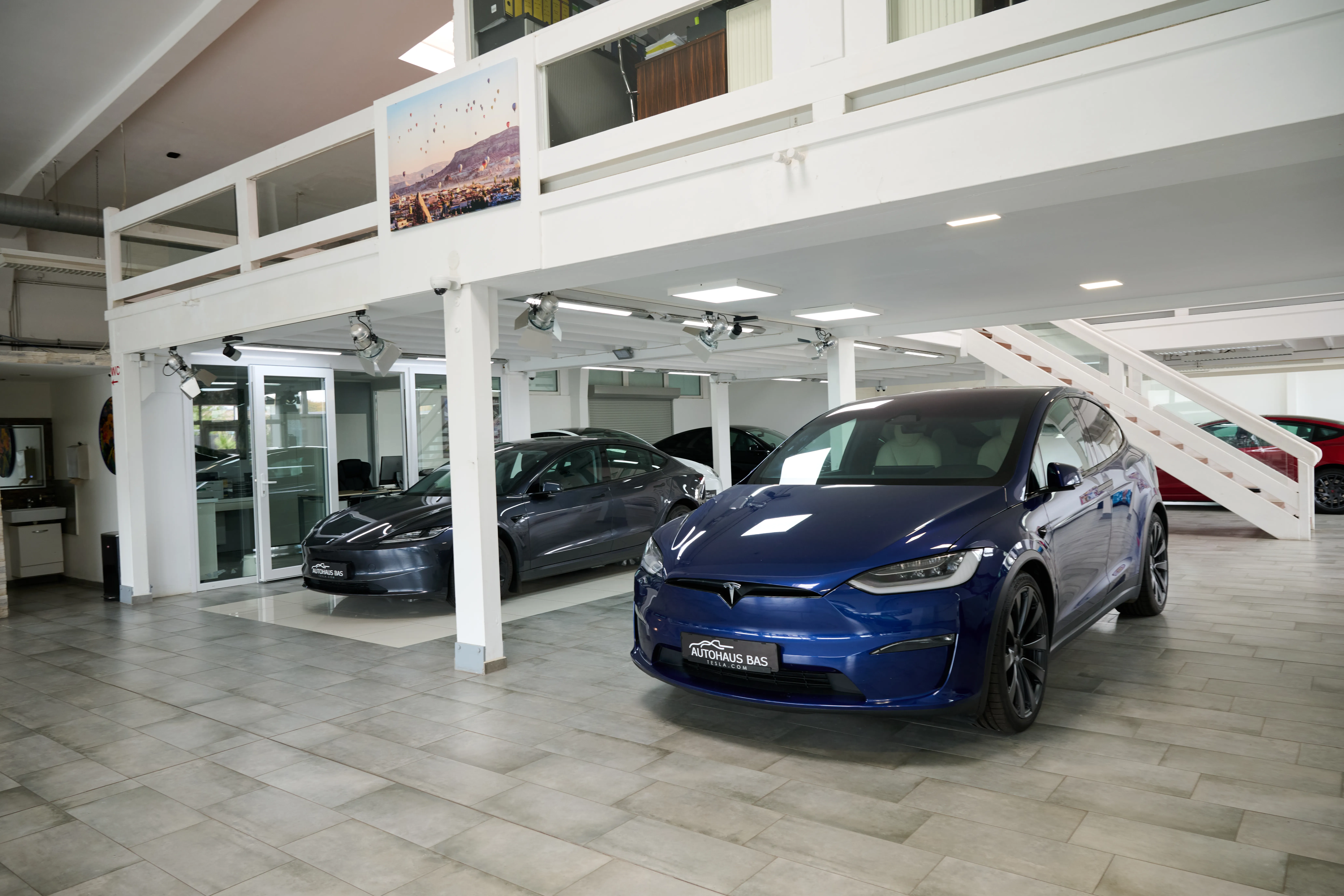 Blauer Tesla Model Y und dunkles Model 3 im Showroom des Autohaus Bas